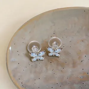 Nahaufnahme von eleganten Schmetterling-Ohrsteckern mit hellblauen Zirkonia und Silberstiften