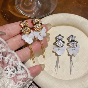 Elegant zircon flower earrings with white resin petals and delicate long metallic tassels.