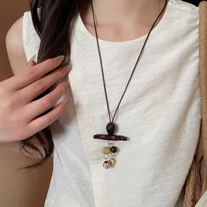 Detail of Bohemian retro wooden pendant necklace worn with a white textured top