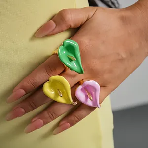 Primer plano de anillos de flores de lirio cala en esmalte de colores dopamina en la mano