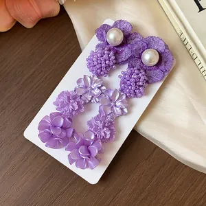 Primer plano de pendientes de flores moradas con perlas en tarjeta de exhibición