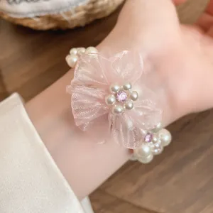 Détail d'un bracelet de fleurs en mousseline rose et perles blanches