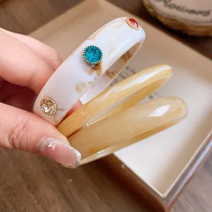 Detailopname van textuur en kleurrijke steentjes op retro marmeren hars armbanden