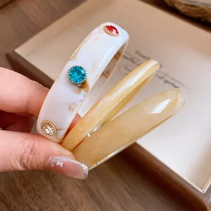 Detailopname van retro marmeren acryl armbanden met fonkelende kleurrijke strass-steentjes