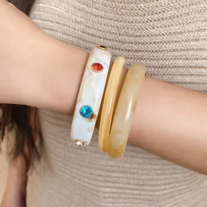Detailweergave van wit en amber marmeren armbanden met ingelegde gekleurde kristallen