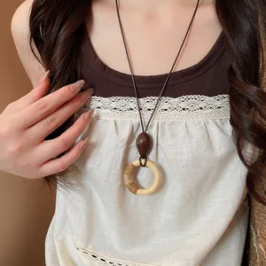Close-up detail of a Bohemian vintage style wooden circle pendant necklace on a model.