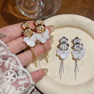 Close-up of elegant gold and silver floral tassel earrings with zircon and resin petals