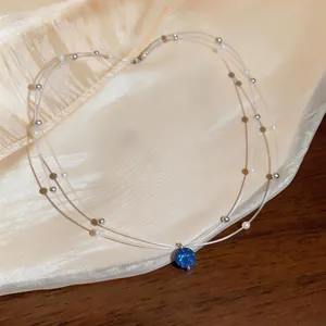 Elegant double-layered necklace with blue zircon pendant and pearl beads on silk backdrop