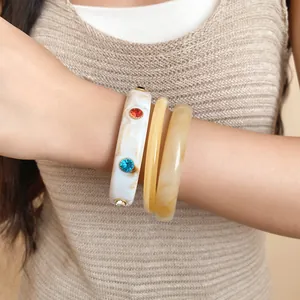 Close-up van retro armband met marmerpatroon en kleurrijke strass-steentjes om de pols