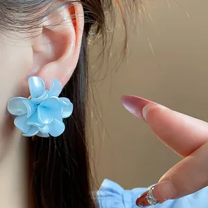 Primer plano de un elegante pendiente con forma de flor azul nacarada en la oreja