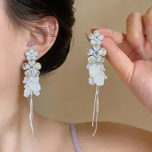 Close-up of elegant zirconia flower earrings with resin petals and long silver tassels