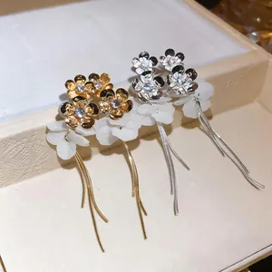 Close-up of elegant floral zircon earrings with long metal tassels and resin petals.