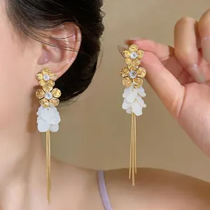 Detailed close-up shot of elegant gold flower earrings featuring resin petals and long tassels
