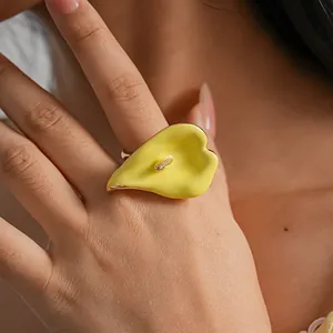 Primer plano detallado que muestra el anillo abierto de esmalte amarillo con lirio cala