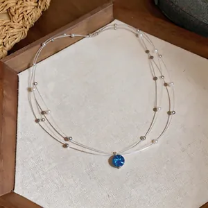 Exquisite close-up detail of multi-layer necklace with blue zircon pendant and pearl beads