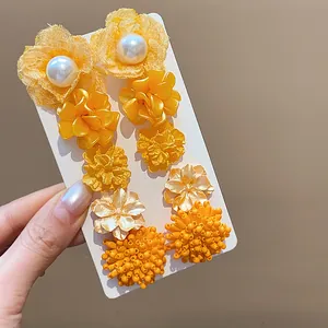 Primer plano detallado de pendientes de flores amarillas con perlas en estilo dopamina