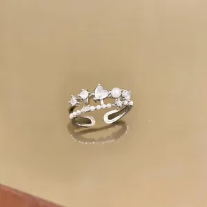 Close-up of a silver open ring featuring heart zircon, pearls, and starburst accents.