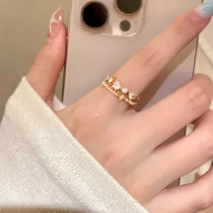 Detailed macro shot of gold layered rings featuring zircon hearts and delicate pearls on finger.