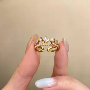 Detailed view of a gold open ring featuring zircon hearts, a pearl, and star motifs.