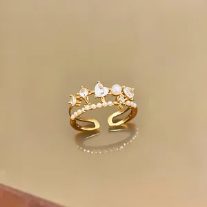 Close-up detail of a gold open ring featuring a heart zircon and delicate pearl.