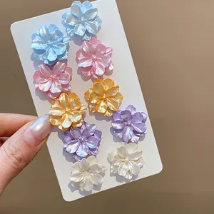 Detalle de cerca de un juego de pendientes de flores de dopamina de colores perla