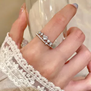 Close-up detail of silver open ring with zircon heart and delicate pearls on finger