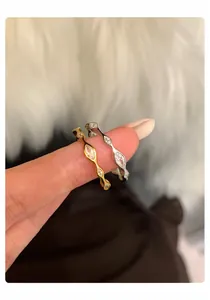 Detail von gewellten Ringen in Gold und Silber mit Zirkonsteinen an einem Finger