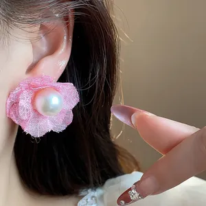 Primer plano detallado de pendiente de flor de malla rosa con perla en la oreja