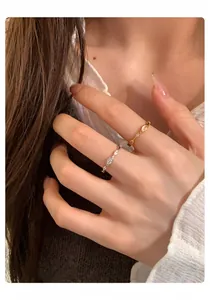 Detaillierte Nahaufnahme von minimalistischen ovalen Zirkon-Ringen in Gold und Silber am Finger.