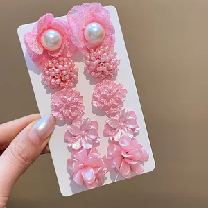 Detalle de un juego de pendientes de flores rosas y perlas con agujas de plata pura