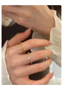 Detailansicht minimalistischer Wellenringe mit Marquise-Zirkonia, an Fingern getragen.