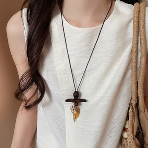 Close-up of Bohemian style long necklace with dark wood and amber resin pendant