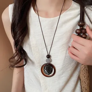 Close-up of a Bohemian round pendant necklace with leaf design worn on a model