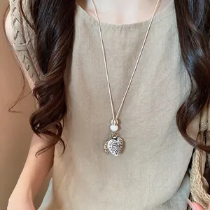 Close-up of bohemian heart pendant necklace with intricate patterns on a sweater chain