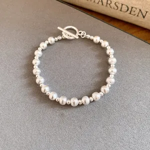 Close-up of elegant silver-toned beaded bracelet with textured finish and toggle clasp.