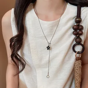 Dettaglio della collana regolabile con ciondolo a fiore nero indossata su un top bianco