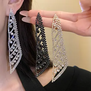 Détail macro de boucles d'oreilles élégantes à pompons en strass en argent, noir et or.