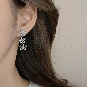 Detailed close-up showing elegant silver triple hollow flower drop earrings on ear