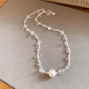 Close-up view of an elegant clear beaded necklace featuring a frosted silver ball pendant