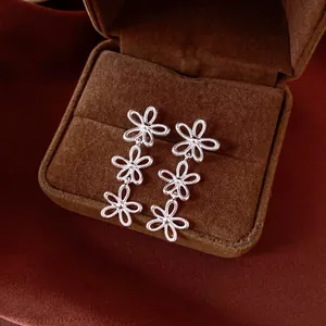 Close-up detail of silver triple hollow flower drop earrings in a jewelry box