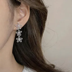 Detailed close-up showing silver hollow flower drop earrings worn elegantly on a model's ear