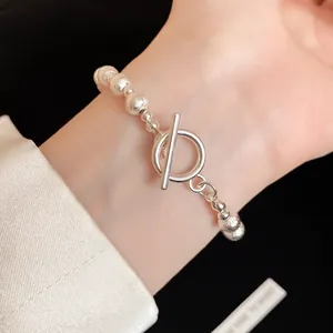 Close-up view of a textured silver beaded bracelet with a toggle clasp on a wrist