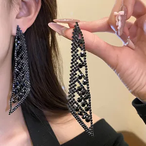 Gros plan d'élégantes boucles d'oreilles à pompons en strass noirs au design géométrique.