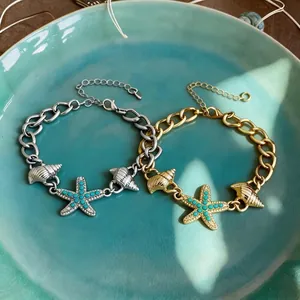 Braccialetti da spiaggia in oro e argento con ciondoli a stella marina e conchiglia su piatto