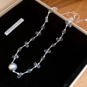 Close-up detail of elegant pearl and crystal choker necklace with textured silver ball pendant
