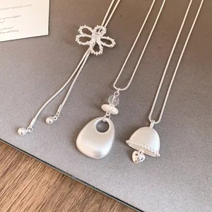 Detail view of silver-toned necklaces with hollow flower and teardrop pendants