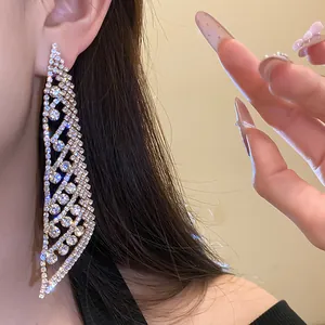 Gros plan de boucles d'oreilles pendantes en strass argentés portées par un modèle