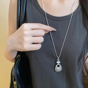 Minimalist matte silver teardrop pendant necklace worn over a casual grey tank top