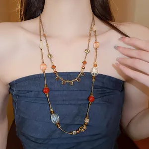 Detailed view of a handmade stackable beaded necklace with crystal and flower charms on model