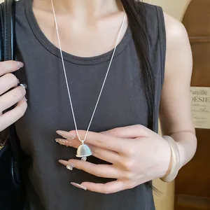 Close-up of zircon hollow flower pendant on a long minimalist silver sweater chain necklace.